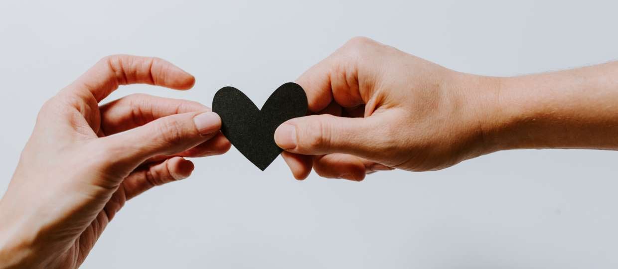 two hands holding a black heart
