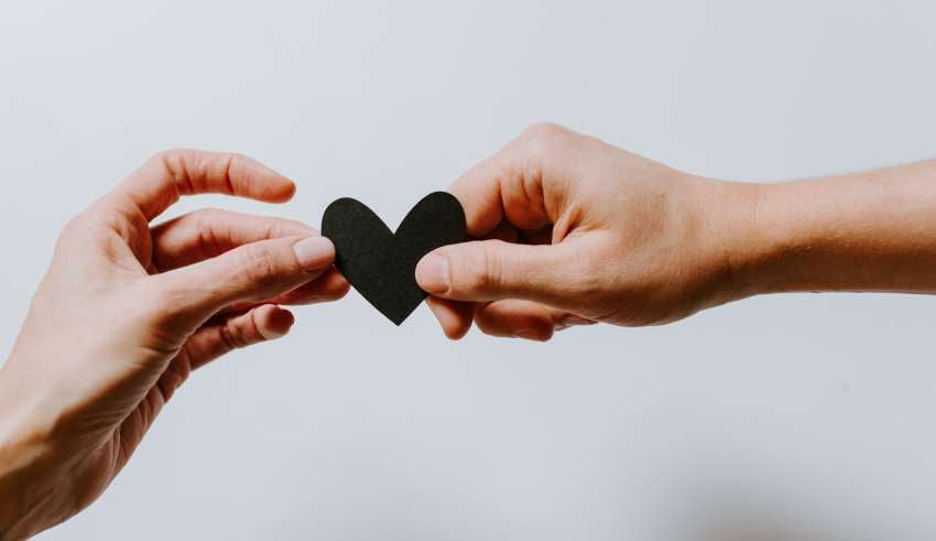 two hands holding a black heart