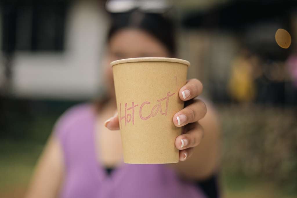 Woman holding out a coffee cup from Hot Cat Speciality Coffee