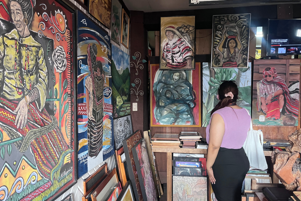 A woman browsing through canvasses of painting at an antique shop